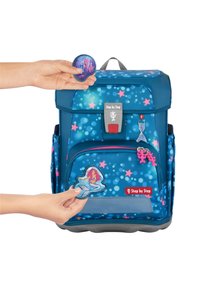 Zaino blu con motivi a stella, spallacci regolabili, tasca frontale e toppe colorate di una sirena e altre decorazioni.