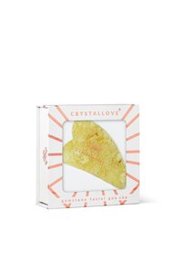 Gua sha do twarzy w kształcie serca, w kolorze żółtym z naturalną teksturą, zapakowane w białe pudełko z koralowymi akcentami i logo.