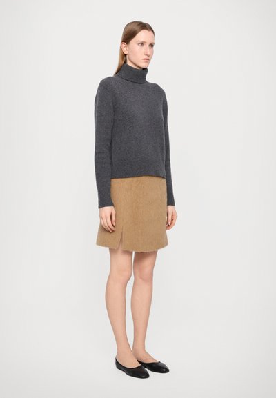 Grey knitted turtleneck sweater paired with a light brown, fuzzy skirt featuring a side slit. Model wears black ballet flats.