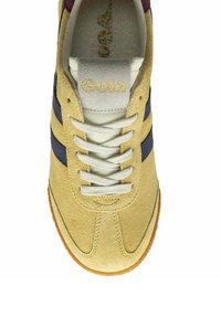 Zapatilla con parte superior de ante amarillo, rayas azul marino, cordones blancos y una lengüeta gris con el logotipo dorado de "Gola"; suela de goma.