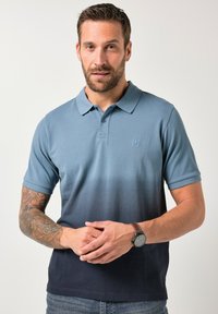 Polo da uomo in misto cotone, sfumatura dal celeste al blu scuro. Maniche corte, collo con bottoni, logo discreto, tessuto strutturato.