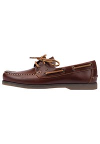 Zapato de barco de cuero marrón con acentos marrón claro, cierre de cordones y detalles de costura. Presenta una suela de goma plana y un diseño de punta redondeada.