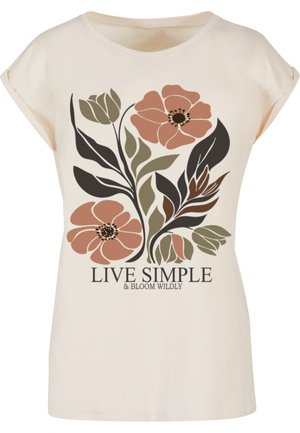 Cremefarvet t-shirt med kortere ærmer, prydet med et stort blomsterdesign i afdæmpet lyserød, grøn og sort, samt teksten "LEV SIMPELT & BLOMST VILDT" trykt nederst.