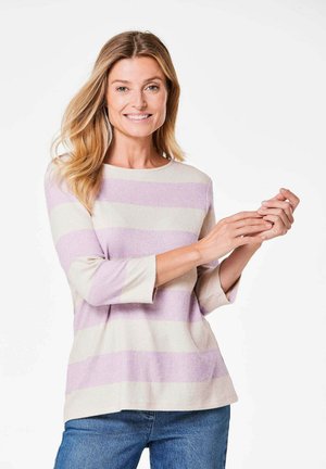 Gestreiftes Langarmshirt in hellem Beige und Lavendel, gerippte Textur, runder Halsausschnitt und lockere Passform, kombiniert mit blauen Denim-Jeans.