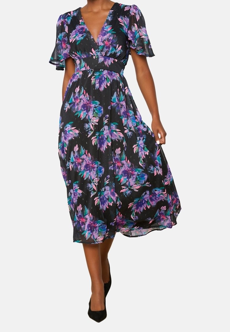 Svart blommig klänning med korta fjäderärmar. Har livfulla lila och teal-blommönster. Lätt, knälång design som inkluderar en djup V-ringning.