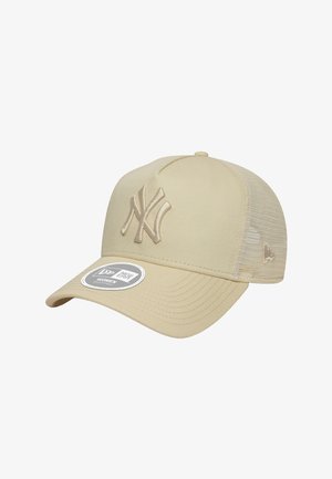 Casquette de baseball beige avec un logo brodé des New York Yankees, visière plate et dos en maille pour la ventilation. Présente une étiquette circulaire sur le devant.