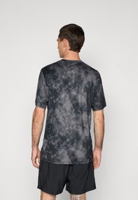 Kortærmet atletisk skjorte i et mørkegrå tie-dye mønster, lavet af et glat, let materiale med rund hals og afslappet pasform.
