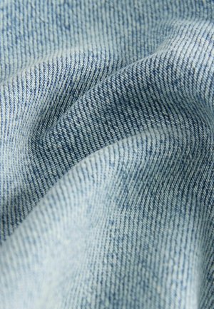 Svijetloplava denim tkanina s tkanjem u dijagonalnom uzorku, s mekim teksturama i suptilnim varijacijama boje. Vidljivo detaljno šivanje.