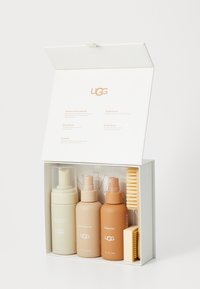 UGG set za čišćenje u bijeloj kutiji. Sadrži tri bočice: bež sredstvo za čišćenje, smeđi obnovitelj, narandžasti zaštitnik. Uključuje žutu četku za zamku.