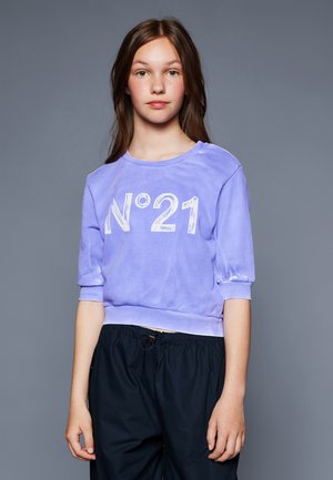 Lila, kurz geschnittenes Sweatshirt mit weißem N°21-Logo auf der Vorderseite, kurzer Ärmel und geripptem Saum. Getragen mit dunklen Hosen.
