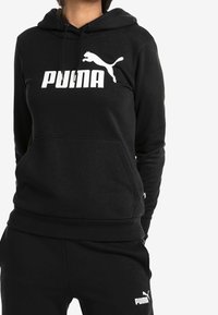 Felpa nera con cappuccio regolabile, tasca a marsupio e logo Puma bianco sulla parte anteriore. Tessuto liscio con polsini e orlo a costine.
