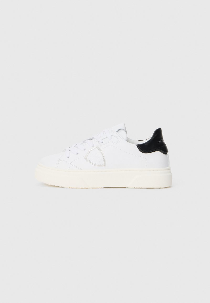 Weiße Low-Top-Sneaker mit einem strukturierten Obermaterial aus Leder, runder Spitze, weißen Schnürsenkeln und einem schwarzen Lederbesatz an der Ferse. Dicke Gummisohle.