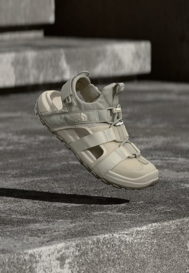 Μπεζ εξωτερικό σανδάλι από ελαφρύ υλικό, με πάνελ από δίχτυ, ρυθμιζόμενους ιμάντες και υφασμένο καουτσούκ πάτο με σχέδιο πέλματος.