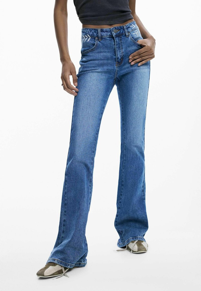 Jeans a zampa di colore blu realizzati in denim, caratterizzati da vita alta, tasche anteriori e dettagli ricamati discreti sulla cintura.