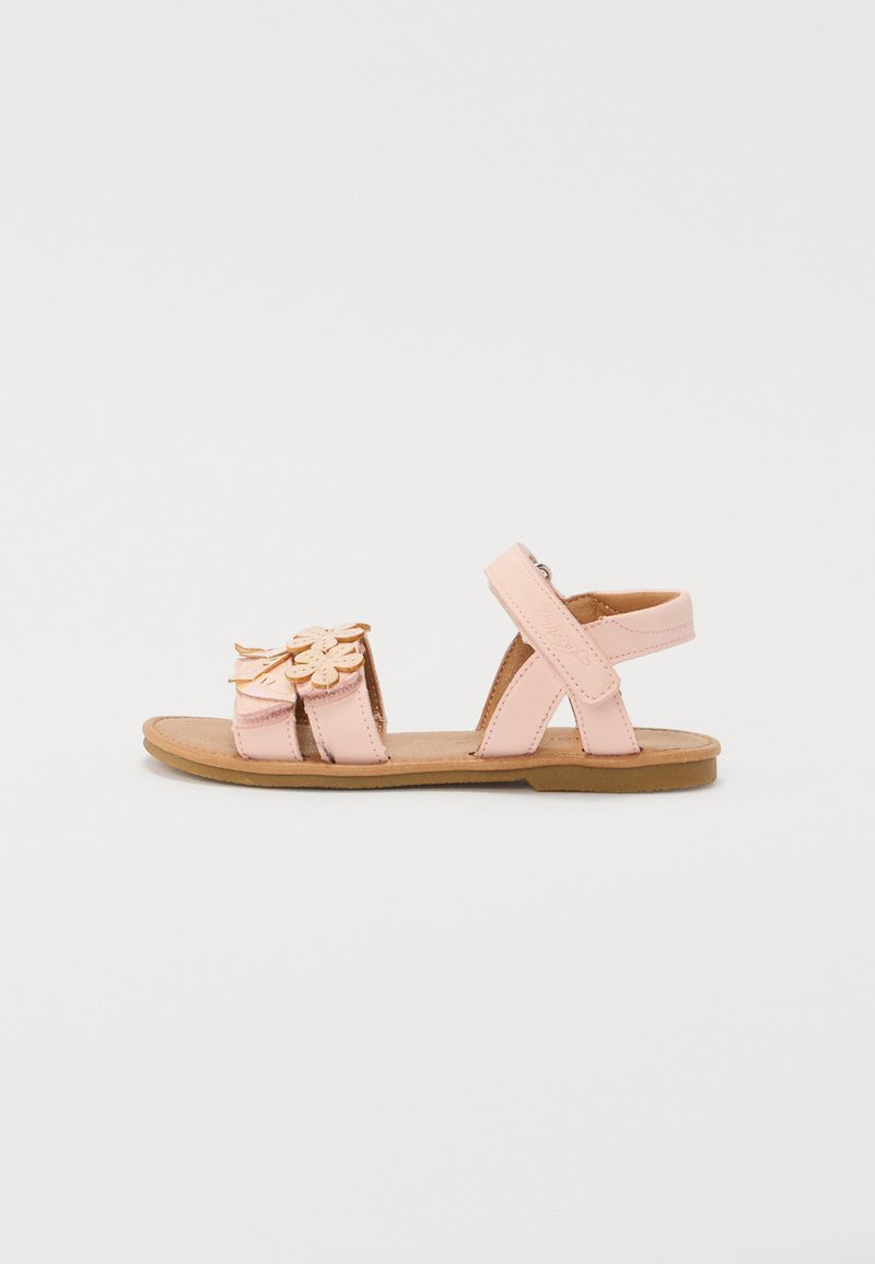 Roosa nahast sandaalid lillede aplikaadiga, reguleeritavad rihmad, lamedad tald ja pruuni tooni sisetald. Avatud disain hingavuse tagamiseks.