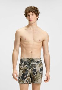 Shorts de bain avec un motif floral en olive, beige et noir, dotés d'une taille élastique avec cordon de serrage et de poches latérales.