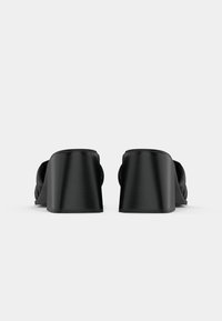 Schwarze Plateausandalen mit einer glatten Lederoberfläche, abgerundeter Zehenpartie und breiten Riemen, die ein mutiges, zurückhaltendes Design bieten.