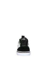 Zapatillas Vans en blanco y negro con un diseño de tablero de ajedrez, con parte superior de ante, cordones y una suela de goma blanca. Vista frontal.