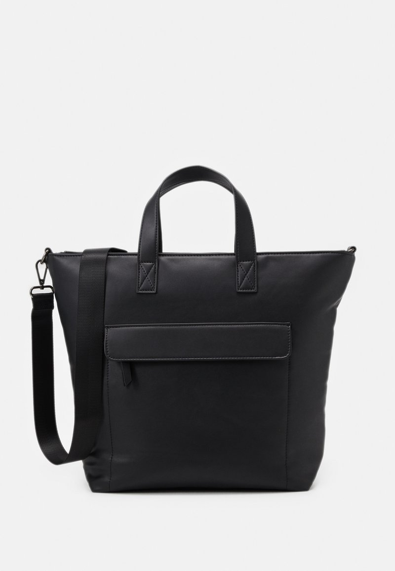 Sac tote en cuir noir avec deux poignées supérieures et une bandoulière amovible. Comprend une poche avant avec un rabat et des accents de couture.