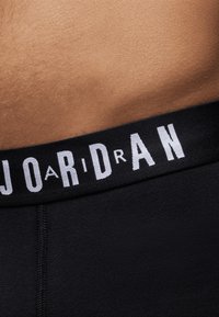 Fekete boxeralsó széles, rugalmas derékkal, melyen a "JORDAN" felirat kontrasztos fehér betűkkel látható. Sima szövettextúra.