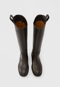 Ψηλές καφέ δερμάτινες μπότες με λεία επιφάνεια, στρογγυλεμένες μύτες και υφασμάτινη επένδυση. Διαθέτουν θηλιές στο πάνω μέρος για εύκολη χρήση.