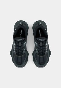 Zwarte sportschoenen met gaaspanelen, getextureerde oppervlakken en een dikke zool. Het ontwerp bevat veters en branding op de tongen.