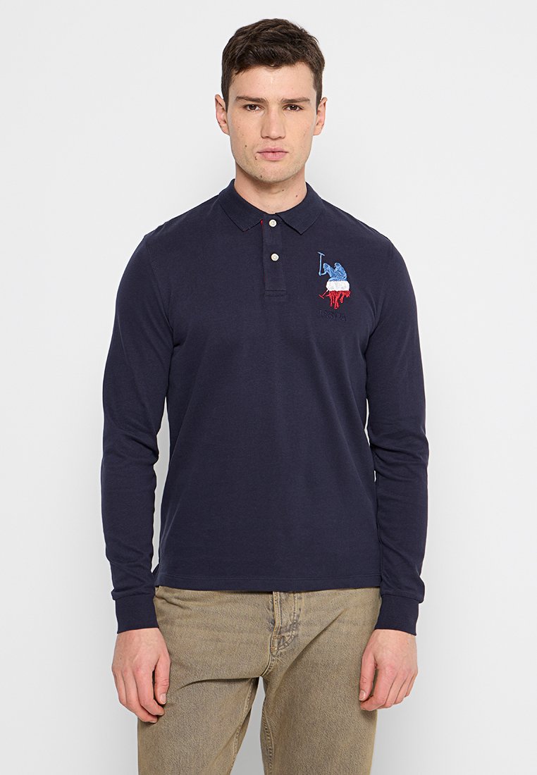 Polo a maniche lunghe di colore blu navy realizzato in cotone, con colletto a bottoni e design ricamato con accenti rossi, bianchi e blu sul petto.