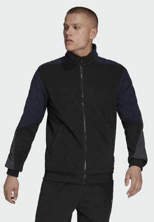 Black zip-up jacket with varied blue accents, featuring a high collar, elastic cuffs, and two side pockets. Soft, textured fabric.