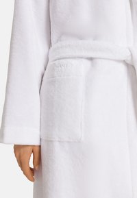Vitt fleece badrock med långa ärmar, ett bälte och en framficka med präglad logotypdetalj. Mjuk textur och följsam finish.