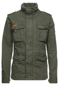 Olivgrön militärjacka i stil med hög krage, fyra framfickor och axelklaffar. Tillverkad av hållbart tyg med en texturerad yta.