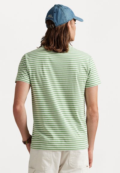 Tricou scurt cu maneci, verde și alb cu dungi, fabricat din bumbac, având guler rotund și o croială lejeră. Purtați cu o șapcă din denim.