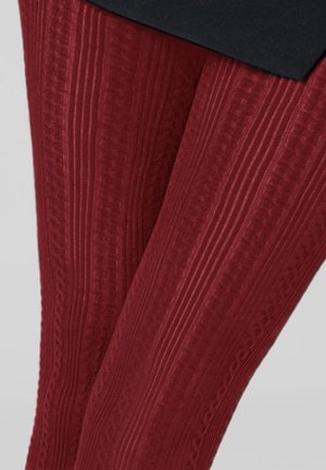 Burgundowe legginsy o teksturowym wzorze z prążkowanymi i warkoczowymi detalami, wykonane z elastycznego materiału, który podkreśla nogi.