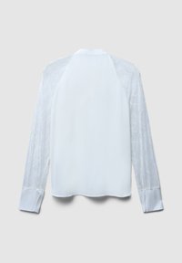 Blusa bianca a maniche lunghe con maniche in pizzo trasparente, schiena semplice e polsini larghi su uno sfondo grigio uniforme.