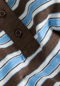 Striped fabric featuring brown, blue, white, and navy lines. Includes a brown button and stitched detailing near the collar area.