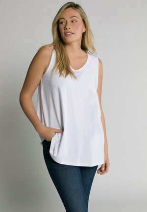 Witte mouwloze top met een ronde hals, gemaakt van een zachte stof, met een relaxte pasvorm en zijzakken, gecombineerd met donkerblauwe jeans.