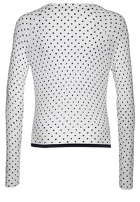 Vit långärmad tröja med marinblå prickar, ribbad nederkant och halsringning. Enkel design med figurnära form och slät yta.