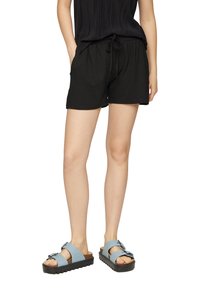Shorts en coton noirs avec une taille élastique et un cordon de serrage. Associés à des sandales bleu clair avec des brides et une semelle épaisse et texturée.