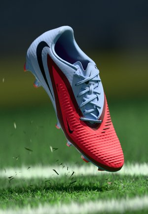 Nike nogometne kopačke u plavoj i crvenoj boji, s teksturiranim gornjim dijelom, crnim akcentima i laganim dizajnom. Detalj na čavlima za prianjanje na travi.