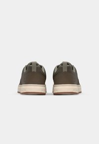 Brown sneakers with a low-top design, feature a textured fabric upper, reinforced heel, and a white midsole with contrasting brown outsole.