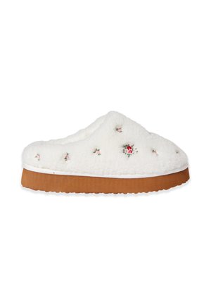 Zapatilla blanca peluda con pequeñas flores bordadas en rosa y rojo y una suela gruesa marrón, vista de perfil.