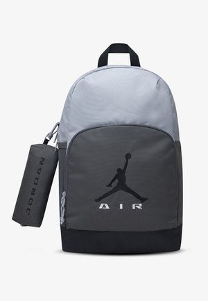 Sac à dos Jordan bicolore gris et noir avec poche avant arborant le logo Jumpman et une pochette cylindrique noire Jordan attachée.