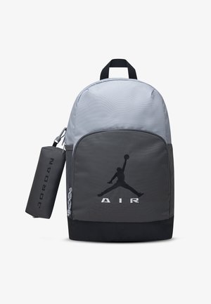 Tweekleurige grijs-zwarte Jordan rugzak met voorvak met Jumpman-logo en eraan bevestigd cilindervormig zwart Jordan tasje.