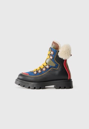 Botte de randonnée colorée avec un mélange de cuir et de tissu, une semelle robuste, des accents multicolores et un détail de col duveteux.