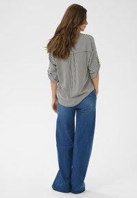 Striped blouse with rolled sleeves, paired with wide-leg blue jeans, showcasing a relaxed fit and soft fabric texture.