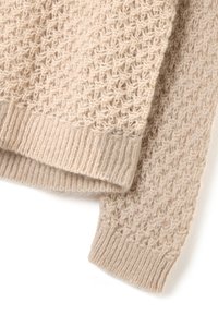 Maglione beige lavorato a maglia con un motivo testurizzato, con polsini e orlo a coste, realizzato in un materiale morbido con una finitura leggermente pelosa.