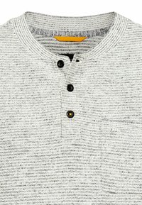 Grau und weiß gestreiftes Henley-Shirt aus strukturiertem Stoff, mit drei schwarzen Knöpfen, einer kleinen Brusttasche und einem gelben Akzent.