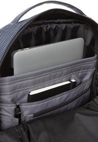 Interno di uno zaino in tessuto grigio con un compartimento per laptop, note e slot per penne; presenta trame lisce e molteplici tasche organizzative.