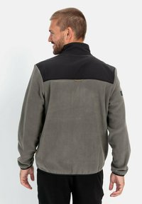 Fleecejacke in Grau mit schwarzem oberen Abschnitt. Verfügt über einen hohen Kragen und verstellbare Bündchen. Minimalistisches Design und glatte Textur.