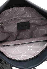 Interno di una borsa a mano in pelle nera con fodera grigia chiara caratterizzata da un motivo a diamante, una tasca con zip e un'etichetta nera tra i dettagli più significativi.