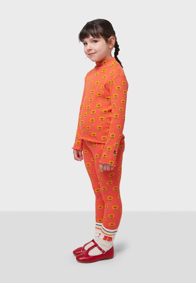 Orange patterned knit long-sleeve top and leggings with sunflower motifs. Paired with red Mary Jane shoes and striped socks.